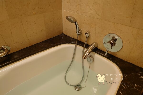 シャングリラ バンコクのデラックスリバービュールームのバスタブの蛇口とシャワー